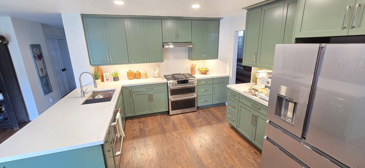Finished kitchen with green cabinets, white countertops, stainless steel appliances, and wood flooring