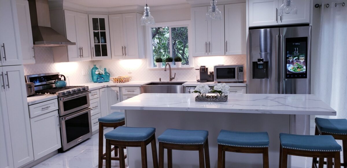 Finished white kitchen with a large island, light countertops, pendant lighting, and blue bar stools