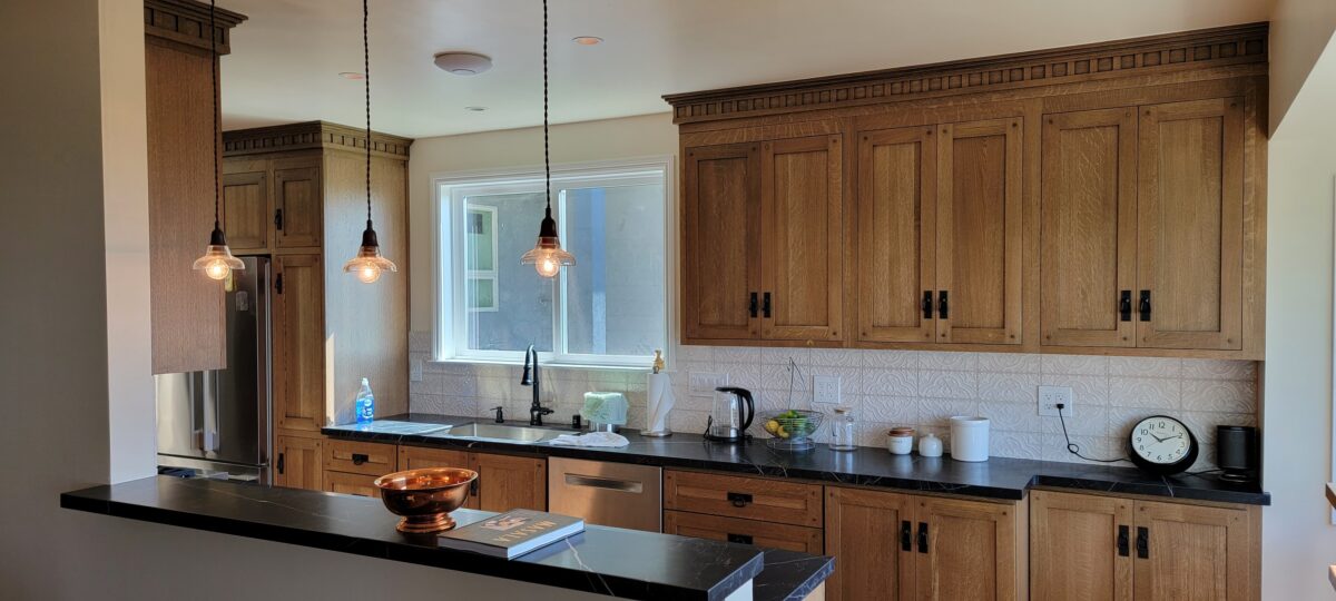 Kitchen with wood cabinets, dark countertops, patterned backsplash, and pendant lighting