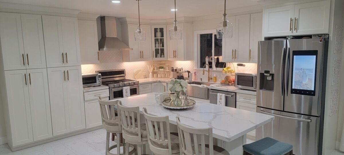 Finished Rojas kitchen with white cabinetry, a large island with seating, glass pendant lights, and stainless steel appliances